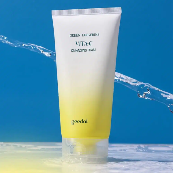 Un tube de Goodal Green Tangerine Vita C Mousse Nettoyante 150 ml se dresse sur un fond bleu avec des éclaboussures d'eau rafraîchissantes tout autour. dakar