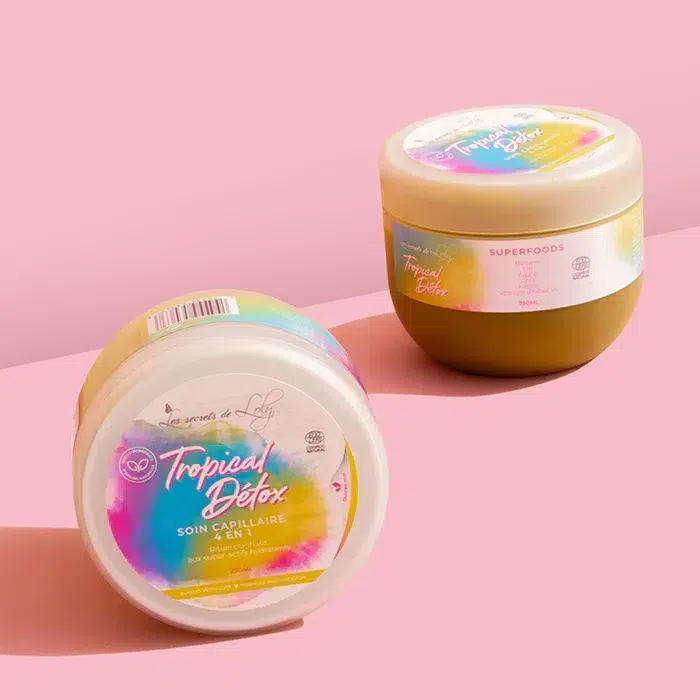 Deux pots vibrants de soins capillaires « Les Secrets De Loly Tropical Détox Soin 4 en 1 Detox Purifiant Lavant et Transition 250 ml » sur fond rose pastel