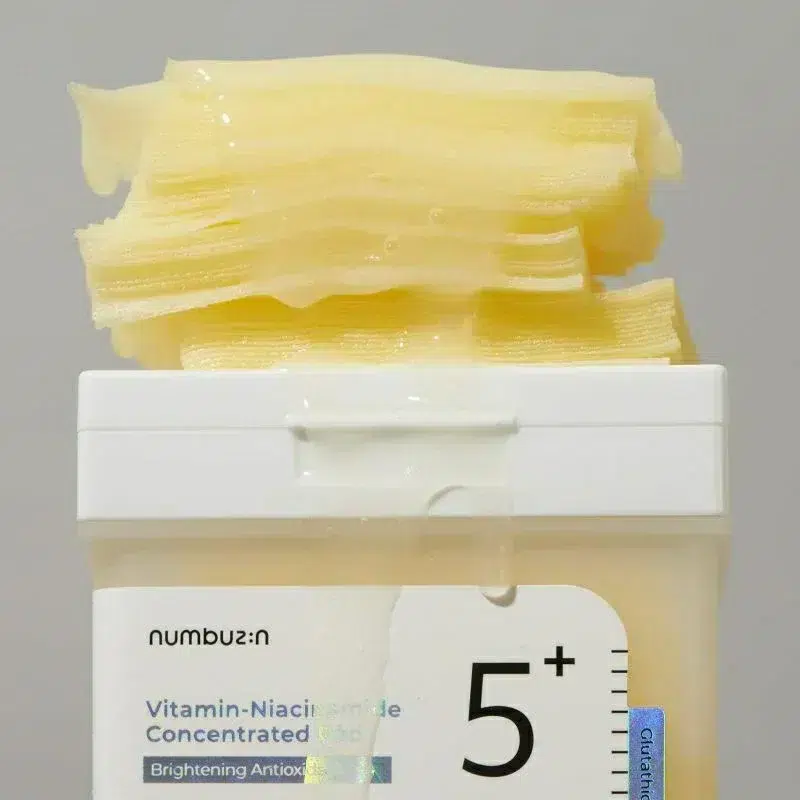 Ouvrir le pot de Numbuzin Tampon Éclaircissant Concentré de Vitamine ET Niacinamide Anti Imperfections 70 Tampons avec une substance gélatineuse jaunâtre débordant du couvercle. dakar